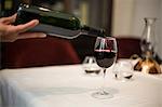 Waiter pouring a glass of red wine in a fancy restaurant