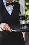 Waitress with tray of red wine in patio of restaurant