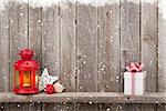 Christmas candle lantern, gift box and decor in front of wooden wall with copy space