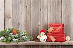 Christmas gift boxes and snowman toy in front of wooden wall. View with copy space