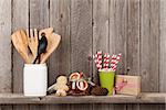 Kitchen utensils and christmas spices on shelf against rustic wooden wall with copy space