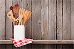 Kitchen cooking utensils on shelf against rustic wooden wall with copy space