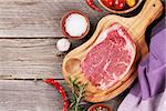 Raw beef steak and spices on wooden table. Top view with copy space