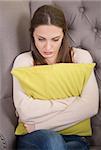Woman with problem on reception for psychologist. Beautiful brunette holding pillow infront on her.