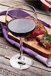 Red wine glass and grilled beef steak with rosemary, salt and pepper on wooden table