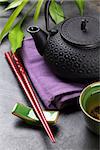 Asian sushi chopsticks, tea bowl and teapot over stone table