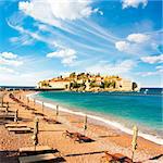 Sveti Stefan Island in Montenegro, Balkans, Adriatic Sea. Beach Chairs at Seashore. European Luxury Summer Resort. Mediterranean Travel Concept. Copy Space.