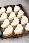 Slices of fresh french bread loaf on baking tray