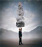 Businessman holds in one hand boulders stack