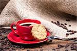 Coffee cup with biscuit spoon and coffeebeans on wooden table