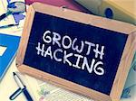 Handwritten Growth Hacking on a Chalkboard. Composition with Chalkboard and Ring Binders, Office Supplies, Reports on Blurred Background. Toned 3d Image.
