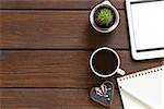 cup of coffee, notepad and an electronic tablet on a wooden background, top view