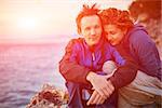 couple standing on the cliff against sea and sunrise sky at early morning