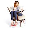 Young woman sitting on a chair with tablet reading e-mails looks very surprised.