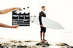 Businessman in front of a clapboard holding is surfboard. Concept about a man starting a new life.