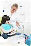 Dentist female showing picture to little girl. Littke brunette lady sitting in the dentist's chair and pointing something on the picture.