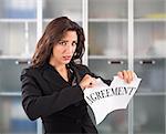 Angry businesswoman tears a sheet document agreement