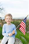 smiling boy holding american flag and celebrating 4th of july