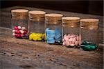 Various pills and capsules in glass containers with caps on dark wooden table