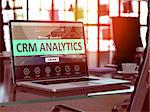 CRM - Customer Relationship Management - Analytics Concept. Closeup Landing Page on Laptop Screen  on background of Comfortable Working Place in Modern Office. Blurred, Toned Image. 3D Render.
