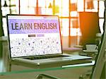 Learn English Concept. Closeup Landing Page on Laptop Screen in Doodle Design Style. On Background of Comfortable Working Place in Modern Office. Blurred, Toned Image. 3D Render.