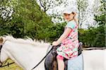 5 year old girl looking at camera while riding a white horse, Germany