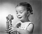 1960s GIRL BOTH HANDS HOLDING A  TOY CANDLE STICK PHONE FUNNY FACIAL EXPRESSION