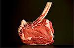 Rib-eye steak with a long bone on a dark surface