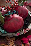 Pomegranates with autumnal sprigs of berries on a pewter plate