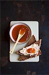 Medlar jam on a bowl and on a slice of toast with cream cheese (seen from above)