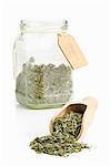 Dried oregano on a wooden scoop and in a storage jar