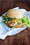 A salmon burger with green lettuce, onions and sauce