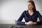 Pensive businesswoman looking away at conference table