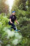 Mid-adult woman cycling through forest