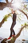 Teenage boy standing on branch