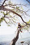 Teenage sitting on branch by sea