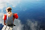 Girl sitting on jetty in water wings