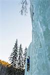 Man climbing up on frozen waterfall