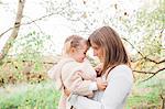 Affectionate mother holding toddler daughter in park