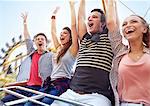 Cheering friends riding amusement park ride