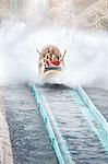 Enthusiastic friends cheering and riding water log amusement park ride