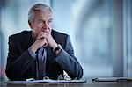 Pensive senior businessman looking away in conference room