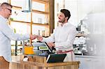 Customer paying worker at cafe cash register