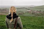 A woman standing in a hilltop looking at the view.