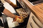 Close-up of a man taking out baked cookies from the oven, Munich, Bavaria, Germany