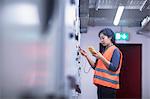 Young female engineer examining control panel with multimeter in an industrial plant, Freiburg im Breisgau, Baden-Württemberg, Germany