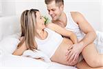 Delighted young parents in bed expecting a little baby