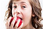 little blue-eyed girl eats a red apple on a white background