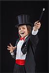 Happy young magician performing a trick with wide gestures - on dark background