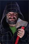 Hooded tough guy with dirty face and bushy beard holding axe - closeup